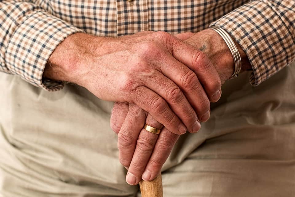 Zoom sur les mains d'un homme âgé posées sur une canne