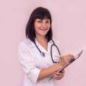 femme médecin remplissant une prescription sur un fond rose