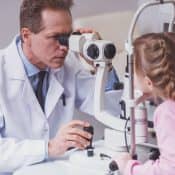 un ophtalmologue utilise un appareil pour évaluer la vision d'une petite fille